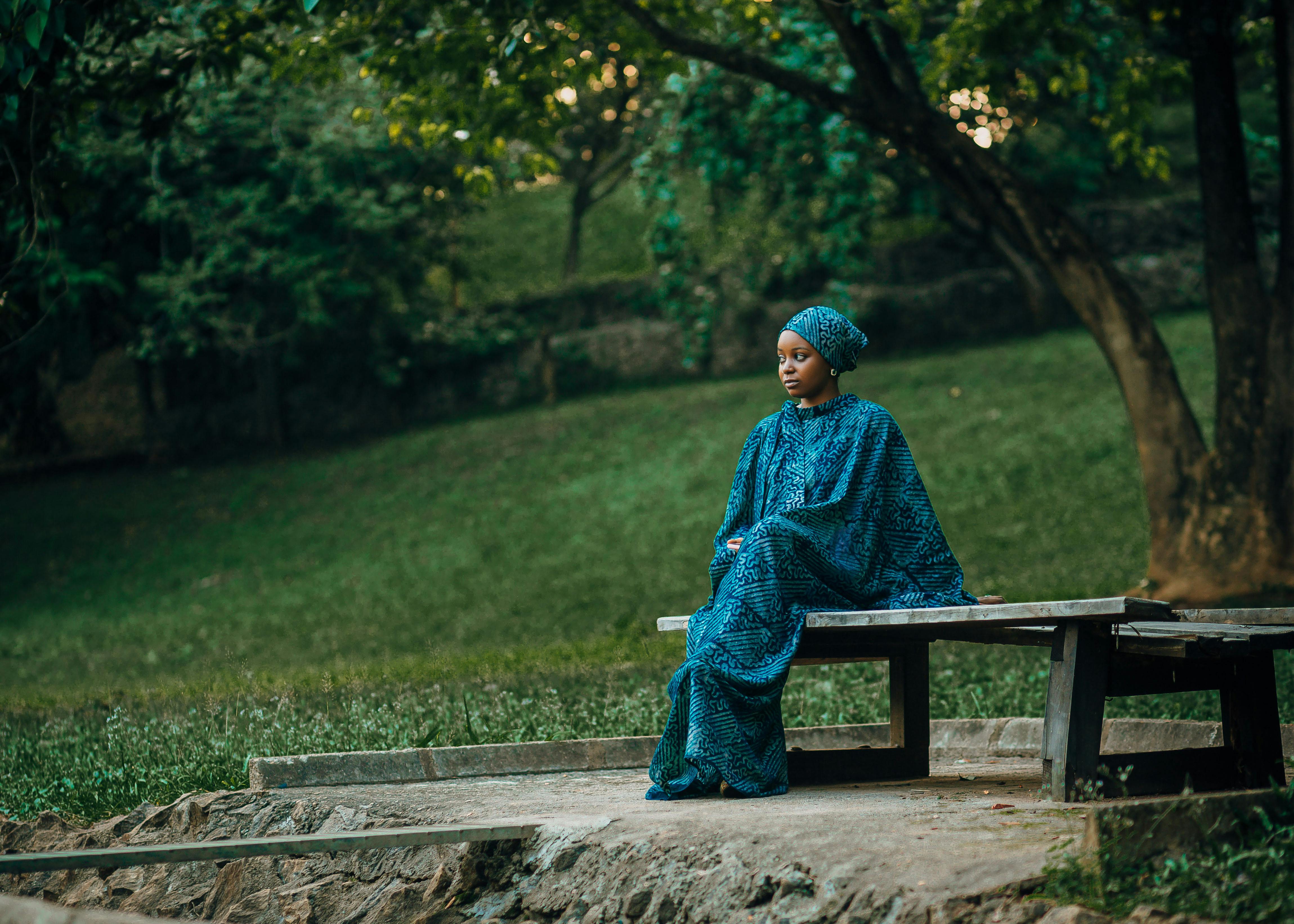 Woman seated outdoors in quiet contemplation surrounded by greenery